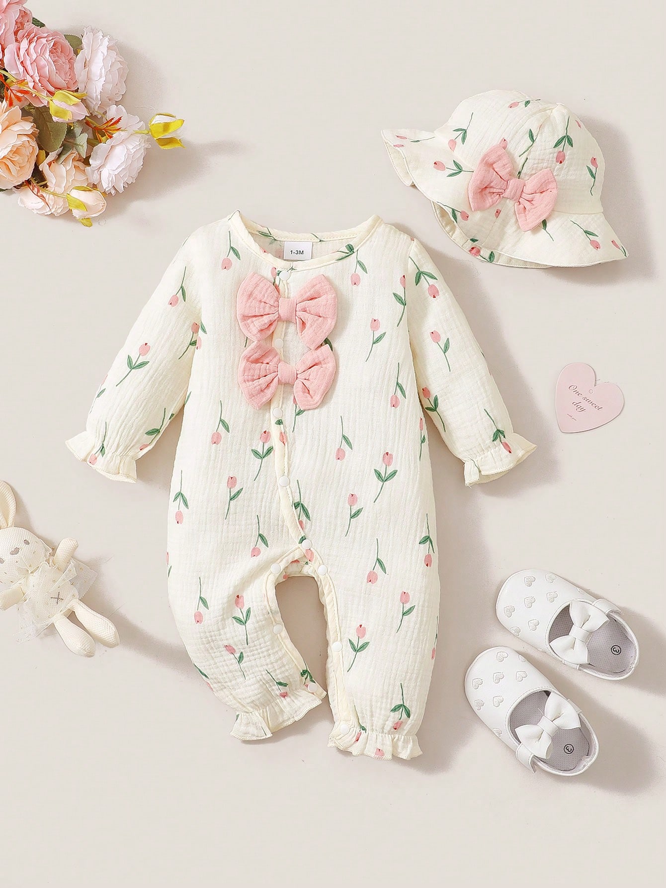 Newborn Baby Girl Romper Floral - ベビーガール用、春・秋に着用できる長袖ガーゼ素材のロンパース2点セット。爽やかなチューリップ柄で、胸元には二重のピンクのリボンがあしらわれ、袖口とズボンの裾には可愛らしいフリルが付いています。お揃いのつば広のバケットハットも付属。股部分が開いているスナップボタン式で、おむつ交換が簡単。新生児が自宅で着用したり、写真撮影の際に着用したりするのに適しており、甘くて愛らしいベビーロンパースセットです。
